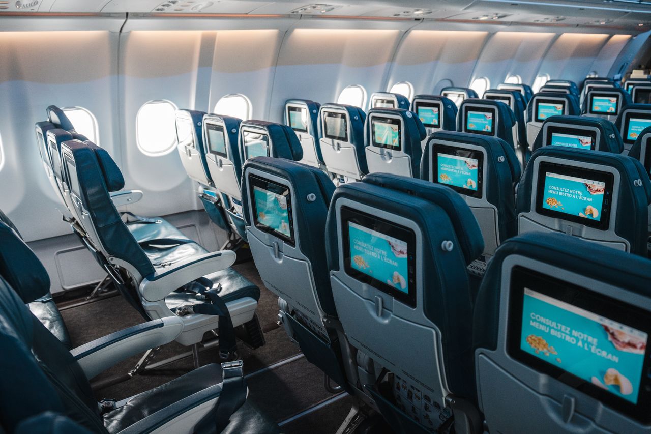Mastering the First Impression: Your intriguing post title goes here Empty airplane interior highlighting rows of seats with touchscreens, offering a modern in-flight experience.