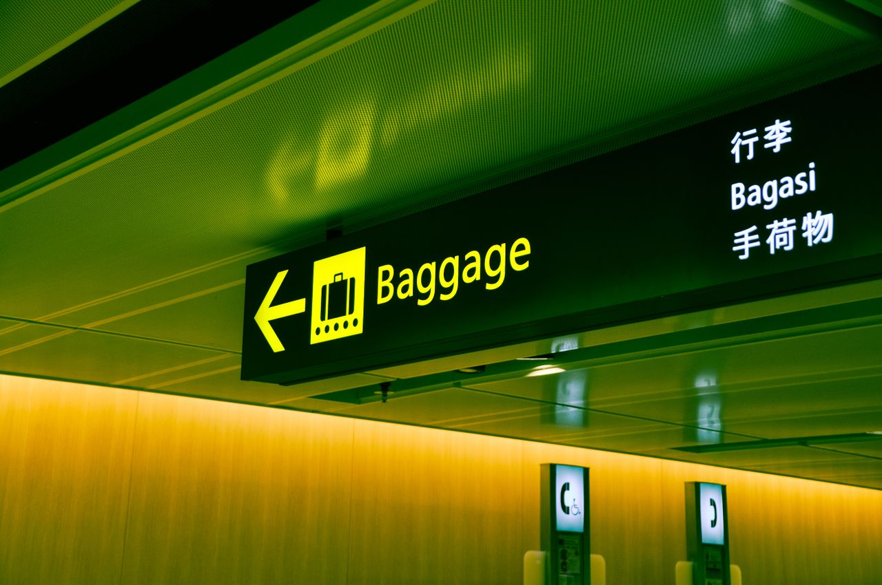 The Art of Drawing Readers In: Your attractive post title goes here Illuminated airport baggage sign with multilingual translations pointing direction for travelers.